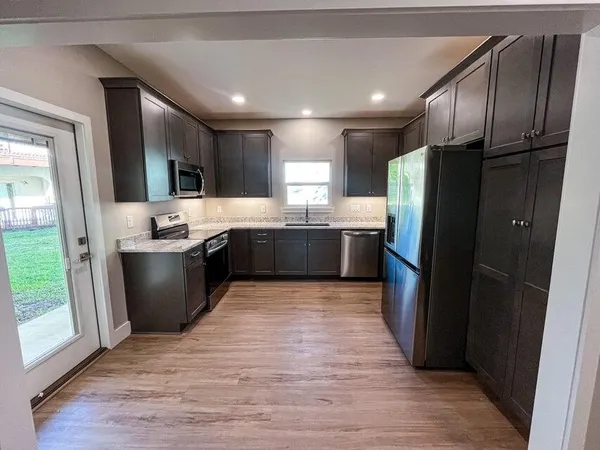 a large kitchen with stainless steel appliances granite countertop a refrigerator a sink a stove and island