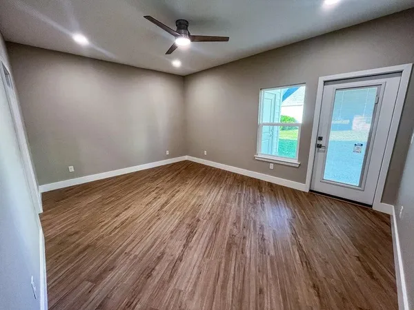 an empty room with wooden floor and windows