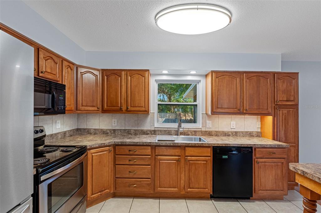 33237 Chancey Road Wesley Chapel, FL 33543 - Photo 17 of 59 a kitchen with granite countertop stainless steel appliances a sink stove and cabinets