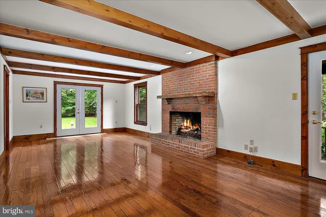 a view of an empty room with wooden floor fireplace and a window