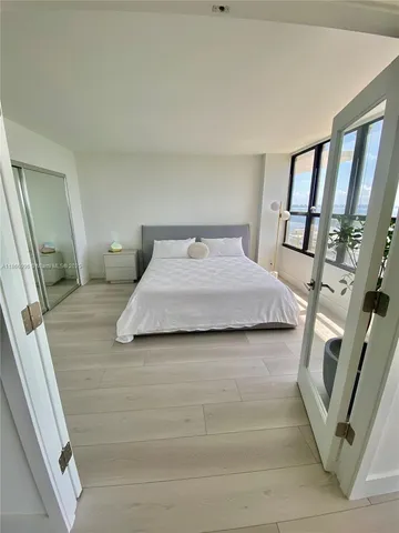 a view of a white building with floor to ceiling window and potted plants