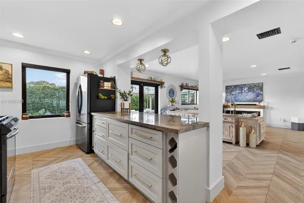 a room with stainless steel appliances kitchen island granite countertop a refrigerator and a sink