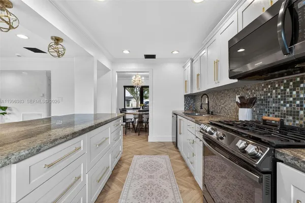a kitchen with stainless steel appliances granite countertop a stove a sink and a microwave