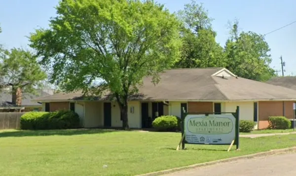 a front view of a house with a garden and trees