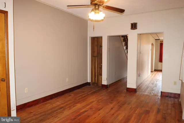 an empty room with wooden floor closet chandelier fan and windows