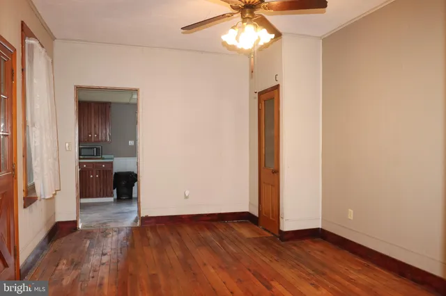 an empty room with wooden floor and ceiling fan