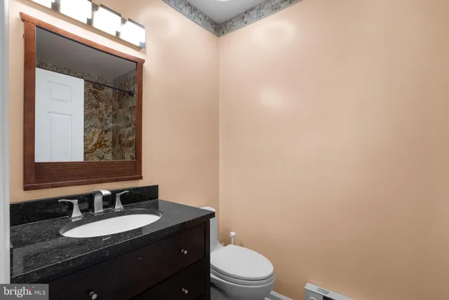 a bathroom with a granite countertop toilet a sink and mirror