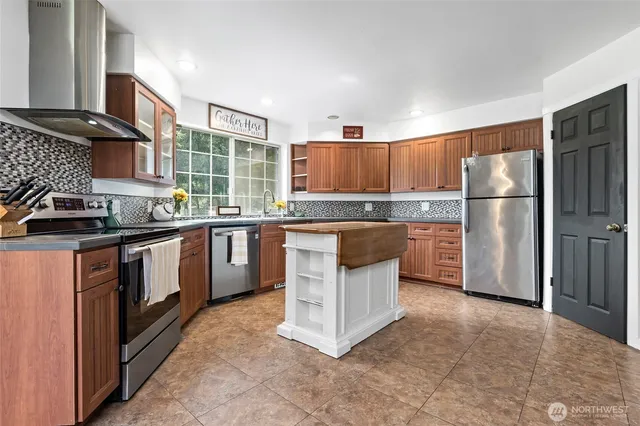 a kitchen with stainless steel appliances granite countertop a stove top oven a refrigerator a sink and dishwasher