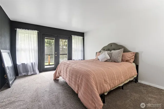a bedroom with a bed and large windows
