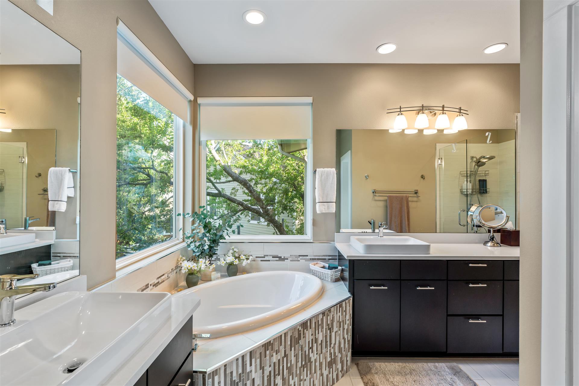 3806 Bull Creek Road, Unit B Austin, TX 78731 - Photo 23 of 37 Large windows frame leafy views in this serene bathroom, featuring a corner soaking tub and dual vanities—perfect for unwinding after a long day at work or a workout.