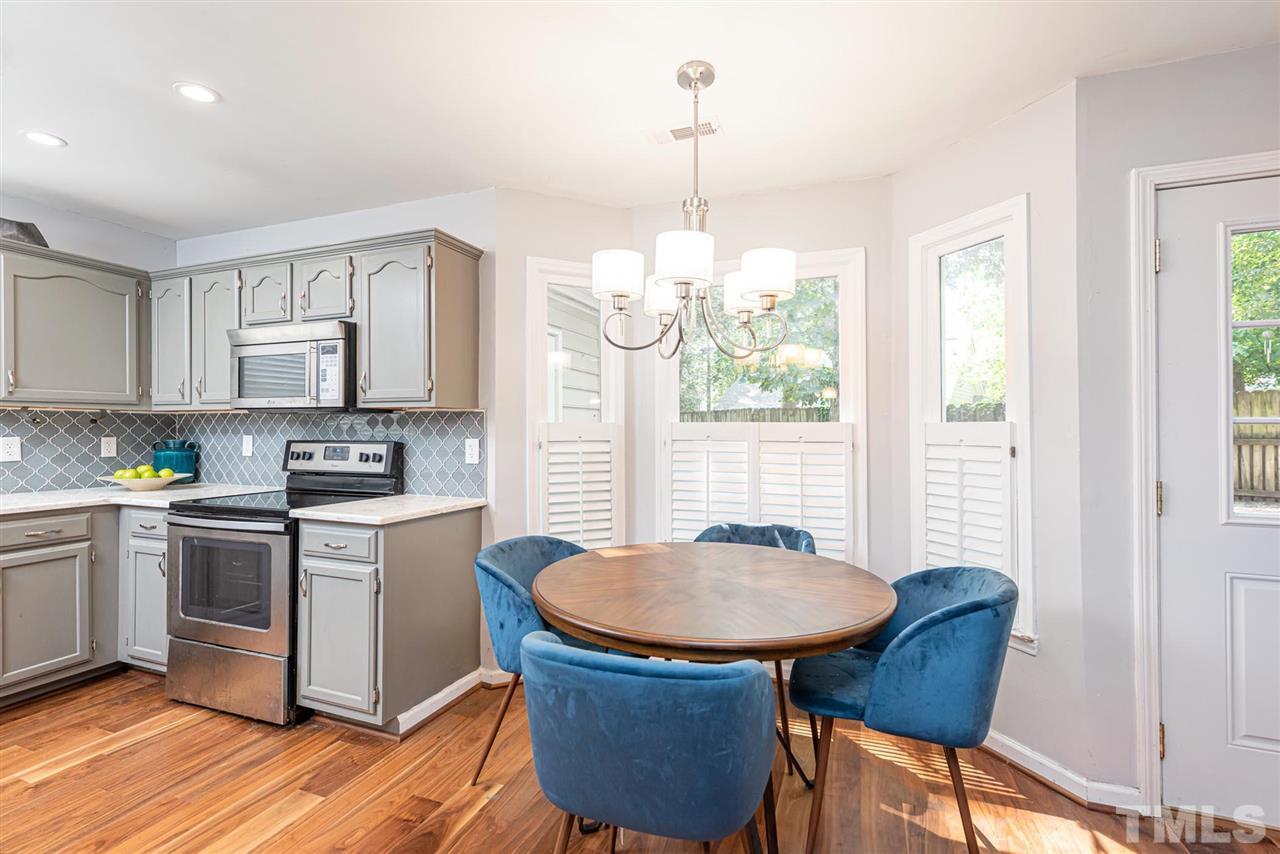 3508 Singleleaf Lane Raleigh, NC 27616 - Photo 6 of 20 a kitchen with stainless steel appliances granite countertop a stove a sink a microwave a dining table and chairs with wooden floor