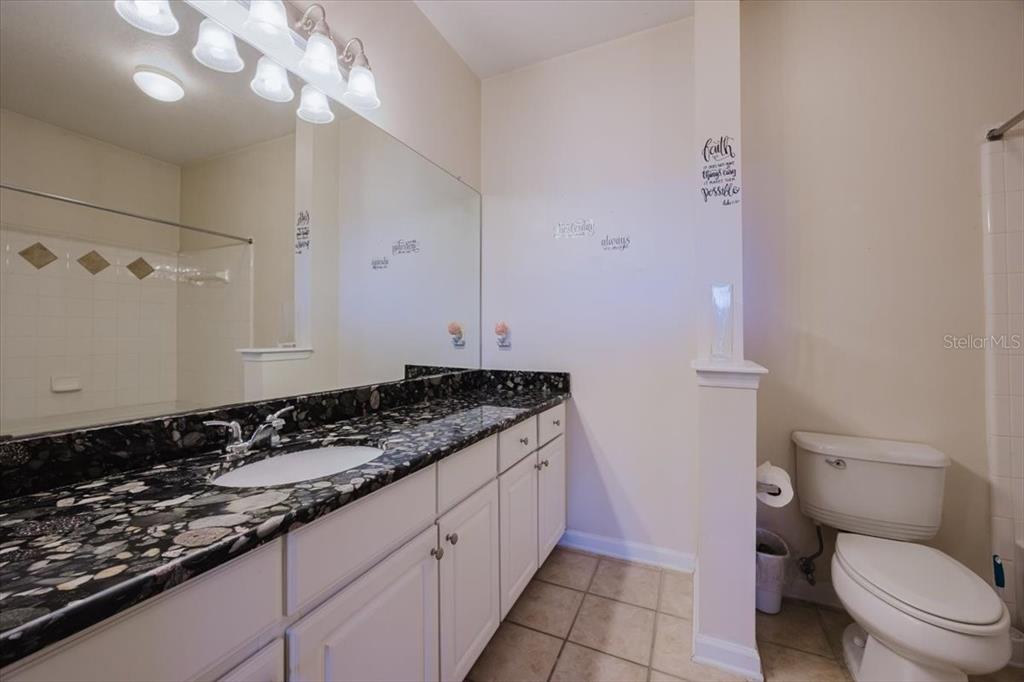 12849 Madison Pointe Circle, Unit 307 Orlando, FL 32821 - Photo 14 of 25 a bathroom with a granite countertop sink a toilet and a mirror