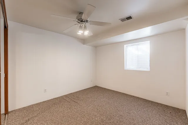 an empty room with a window and a fan