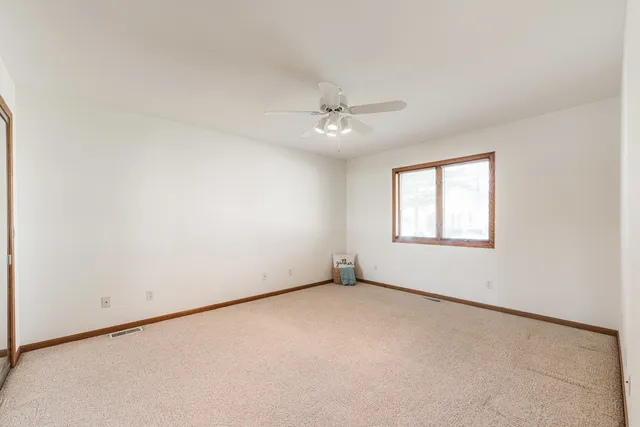 an empty room with a window and a ceiling fan