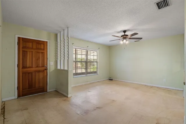an empty room with windows and fan