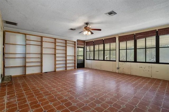 an empty room with windows and fan