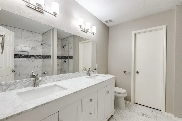 a bathroom with a double vanity sink mirror and toilet
