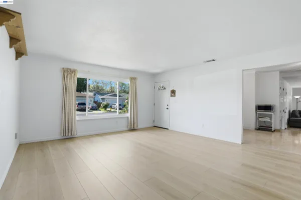 a view of an empty room with a window and wooden floor