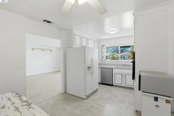 a kitchen with white cabinets and refrigerator