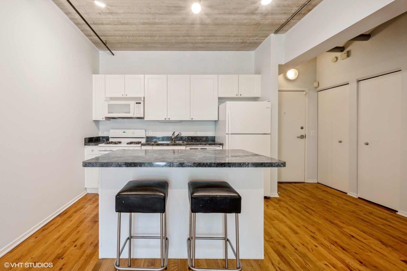 1440 South Michigan Avenue, Unit 322 Chicago, IL 60605 - Photo 5 of 11 a kitchen with kitchen island granite countertop a table chairs stove and cabinets