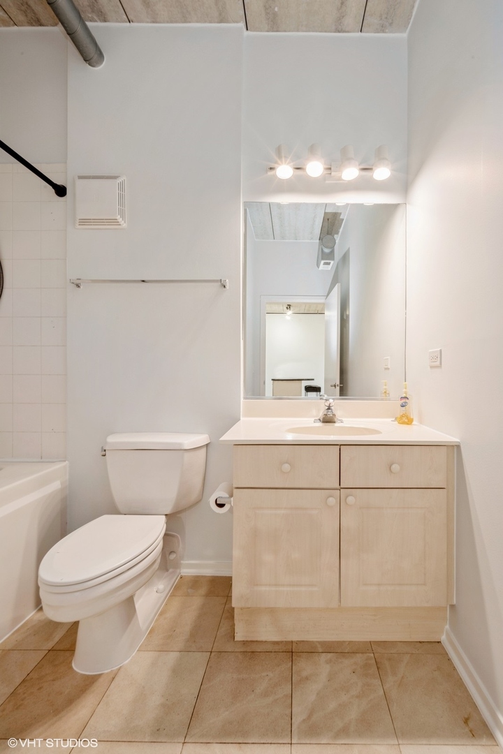 1440 South Michigan Avenue, Unit 322 Chicago, IL 60605 - Photo 9 of 11 a bathroom with a sink a toilet and mirror
