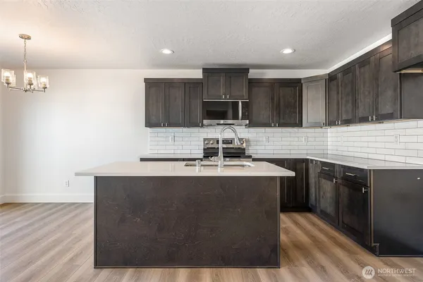 a kitchen with kitchen island a stove a sink a refrigerator and cabinets