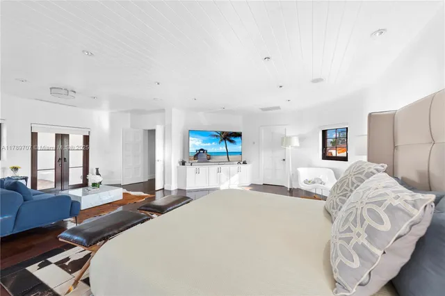 a large bedroom with a large bed and a flat tv screen on dresser