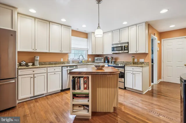 a kitchen with a refrigerator stove cabinets and wooden floor