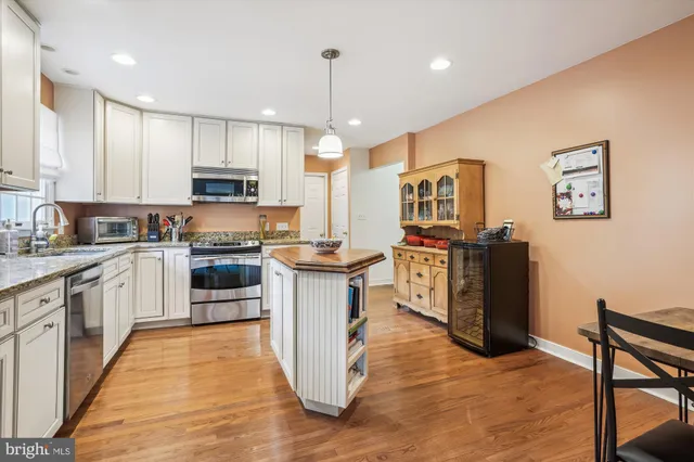 a kitchen with stainless steel appliances granite countertop a refrigerator a stove top oven a sink dishwasher and white cabinets