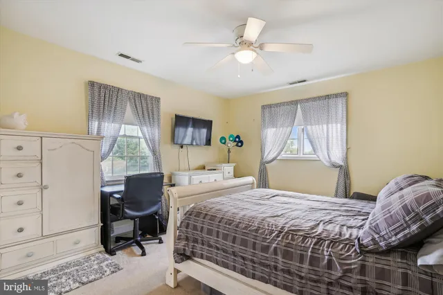 a bedroom with a bed a chair and dresser with the front door