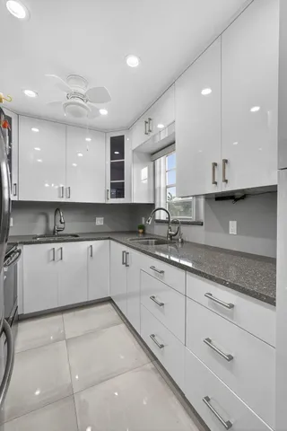 a large kitchen with granite countertop a sink and white cabinets