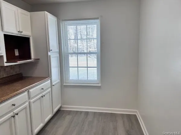 a view of a kitchen with white cabinets and wooden floor