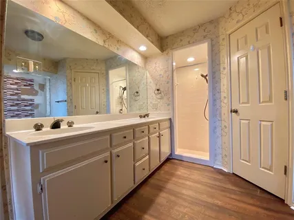 a spacious bathroom with a double vanity sink a mirror and a shower