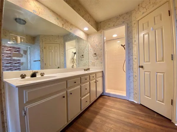 a spacious bathroom with a double vanity sink a mirror and a shower