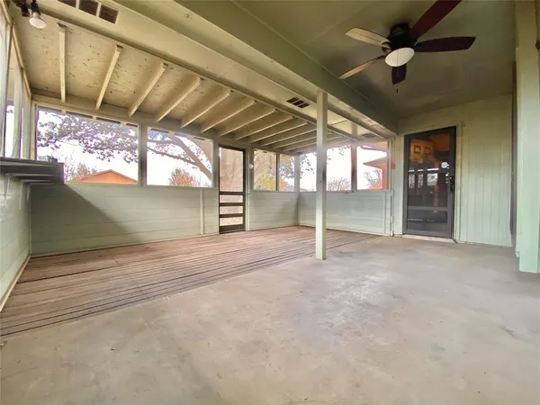 a view of an empty room with a fireplace and a ceiling fan