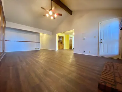 an empty room with wooden floor chandelier fan and windows