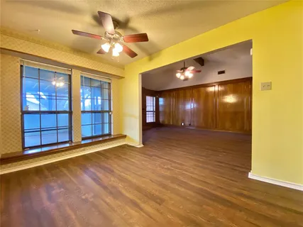 a view of an empty room with window and wooden floor