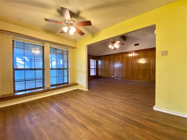 a view of an empty room with window and wooden floor