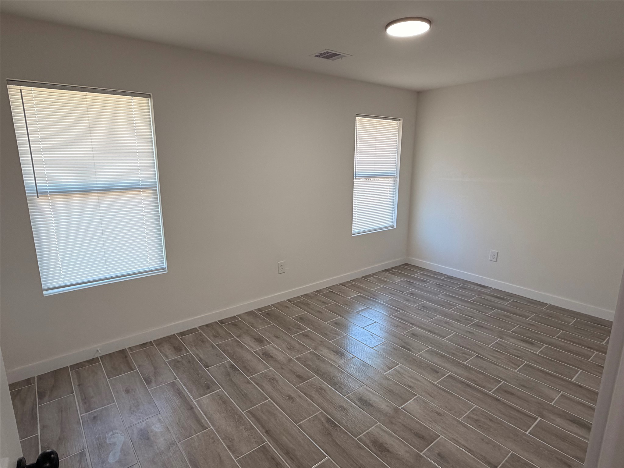 5842 Beldart Street Houston, TX 77033 - Photo 5 of 24 an empty room with wooden floor and windows