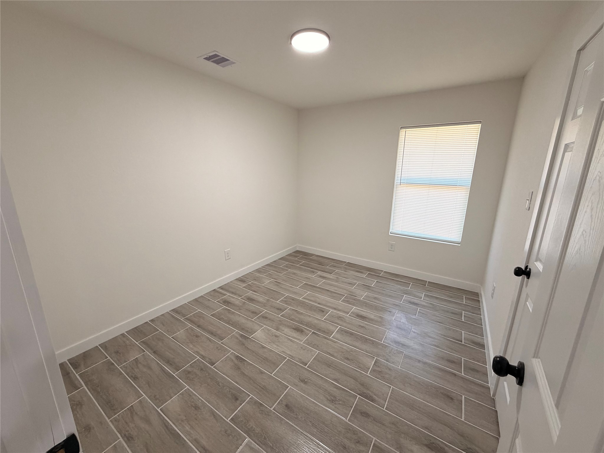 5842 Beldart Street Houston, TX 77033 - Photo 9 of 24 an empty room with wooden floor and windows