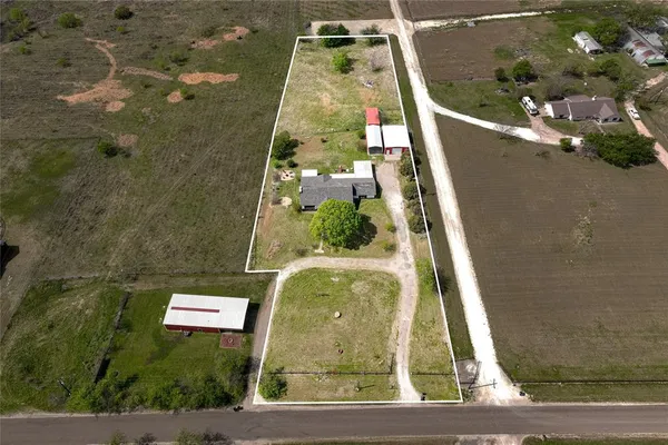 a view of a lake with lawn chairs and large trees