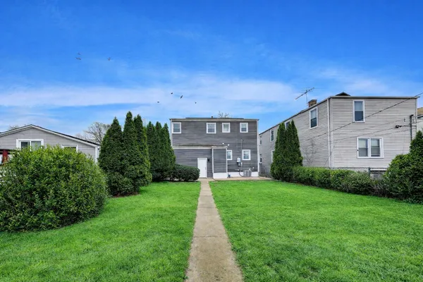 a view of a brick house next to a yard with big trees