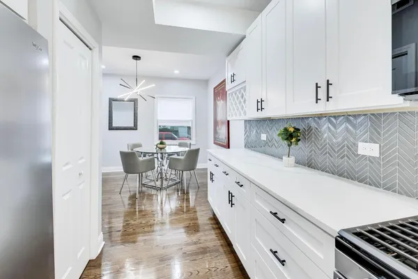 a kitchen with stainless steel appliances a white table chairs and a refrigerator
