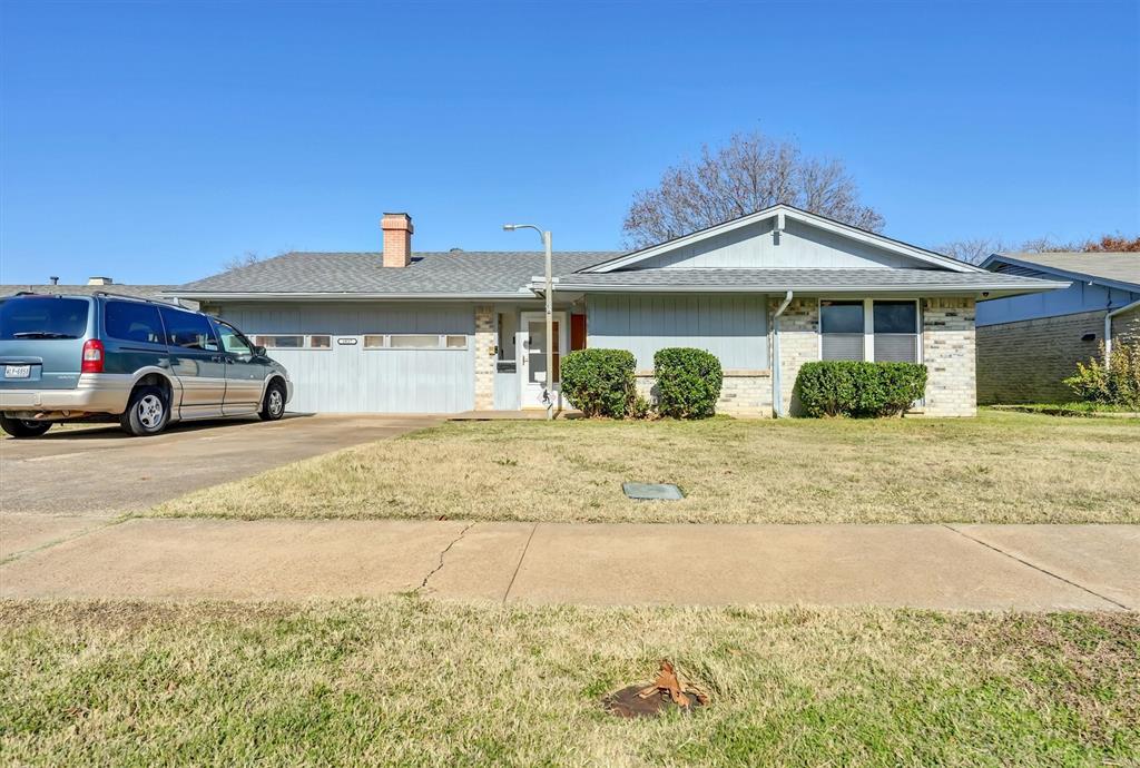 Ranch-style house featuring a front lawn, brick siding, concrete driveway, an attached garage, and a chimney