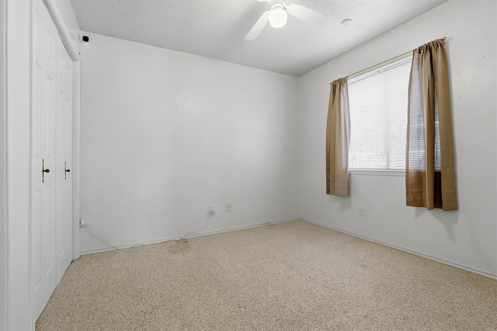 1817 Indian School Road Garland, TX 75044 - Photo 12 of 40 Unfurnished bedroom with a closet, a textured ceiling, a ceiling fan, and carpet