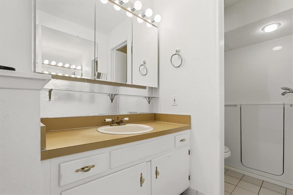 1817 Indian School Road Garland, TX 75044 - Photo 17 of 40 Bathroom featuring vanity, light tile patterned floors, a textured ceiling, and shower / tub combination