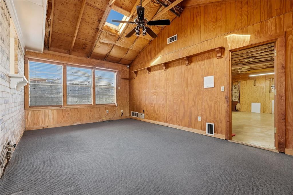 1817 Indian School Road Garland, TX 75044 - Photo 31 of 40 Empty room featuring wooden walls, a skylight, ceiling fan, carpet floors, and high vaulted ceiling