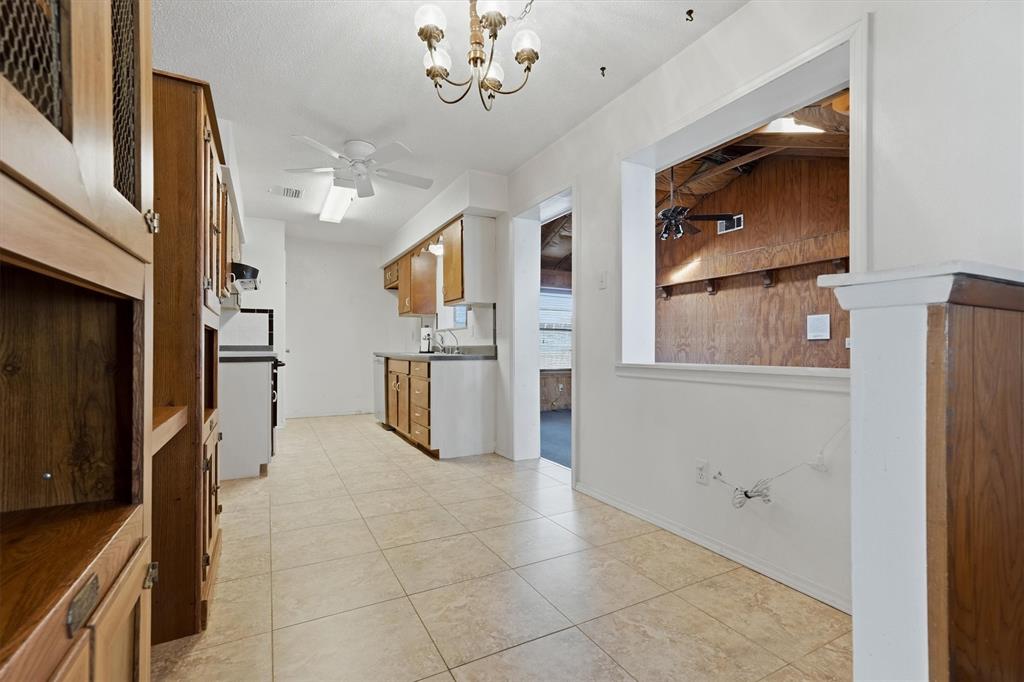 1817 Indian School Road Garland, TX 75044 - Photo 5 of 40 Kitchen featuring a ceiling fan, brown cabinets, light tile patterned floors, a chandelier, and stove