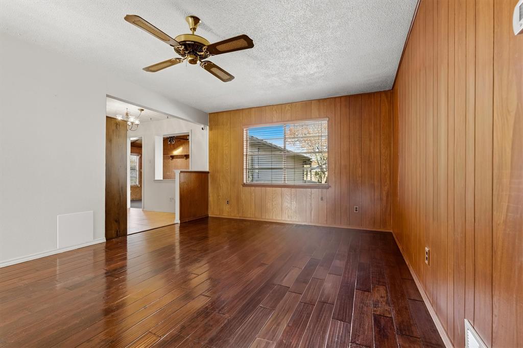 1817 Indian School Road Garland, TX 75044 - Photo 6 of 40 Empty room with wooden walls, hardwood / wood-style floors, a textured ceiling, and a ceiling fan