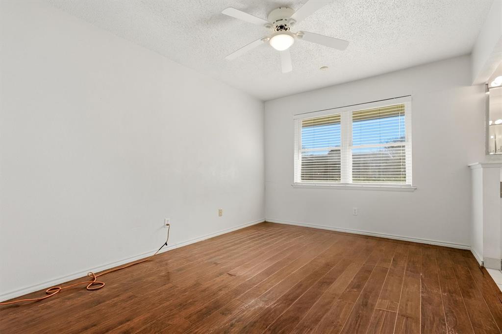 1817 Indian School Road Garland, TX 75044 - Photo 10 of 40 Unfurnished room with a textured ceiling, hardwood / wood-style flooring, and ceiling fan